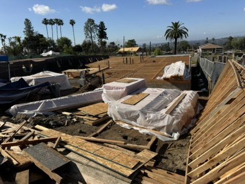 Active construction on Altadena property featuring lumber and drainage material staging