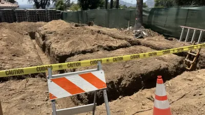 Concrete forming in progress for retaining wall with visible rebar reinforcement and black drainage pipe being installed through hillside slope on Altadena fire rebuild site