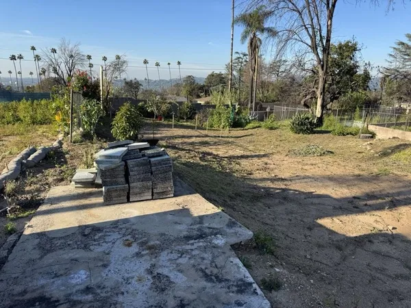 Altadena residential site with existing concrete slab and mature trees before drainage plan construction