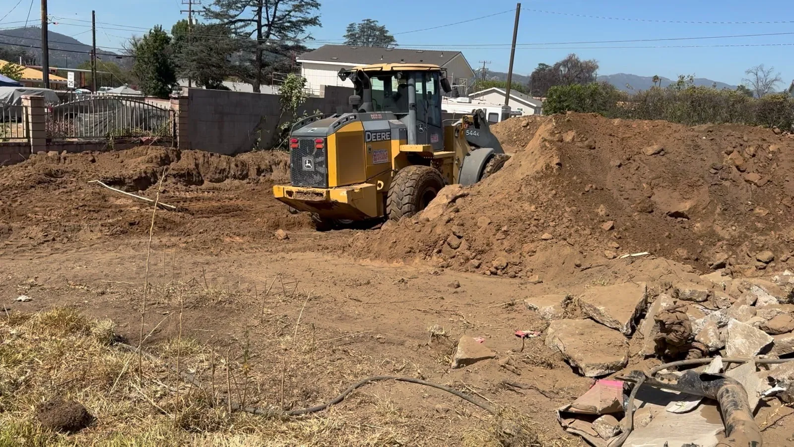 Foundation trench excavation at the Glenrose Avenue Altadena fire rebuild with a Deere 544K wheel loader digging along the curb line