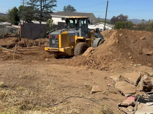 Foundation trench excavation at the Glenrose Avenue Altadena fire rebuild with a Deere 544K wheel loader digging along the curb line