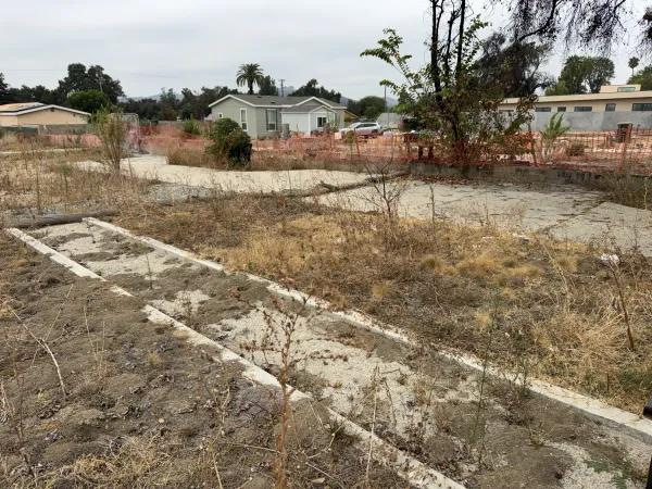 Cleared Altadena lot on W Mendocino Ave showing post-fire demolition concrete footings and foundation strips, prepped for drainage plan and grading work
