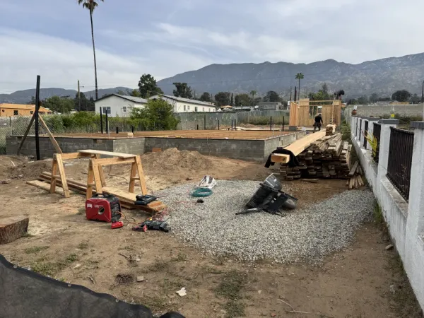 Newly poured concrete foundation with lumber and portable power equipment at Altadena fire rebuild