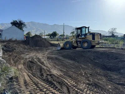 Yellow Caterpillar wheel loader on Altadena construction site with mountain backdrop