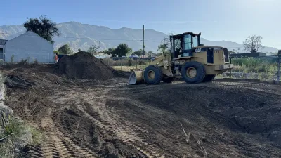 Yellow Caterpillar wheel loader on Altadena construction site with mountain backdrop