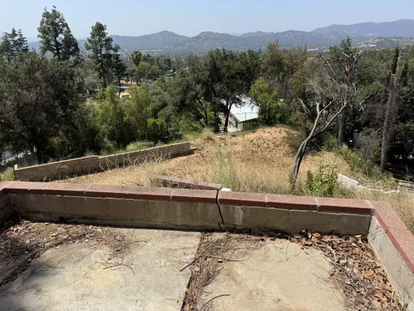 Existing hillside site showing terraced retaining walls and steep topography