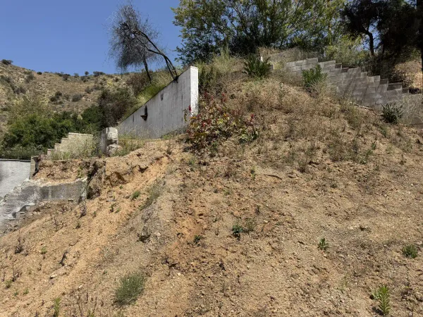 Steep hillside with existing concrete structures requiring grading redesign