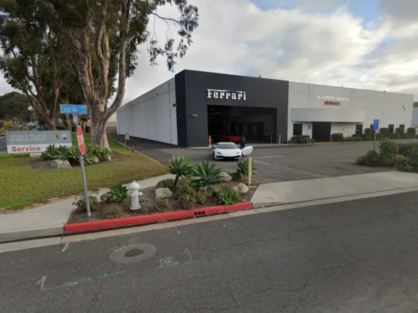 Ferrari and Maserati of Newport Beach service center showing modern commercial building, extensive asphalt paving, concrete curbing, landscaping, and fire hydrant integration