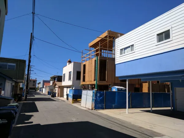 Existing alley conditions at 18th Street Hermosa Beach project showing narrow asphalt alley, overhead utilities, and proximity to adjacent structures