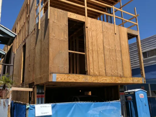 Multi-story wood-frame construction on 18th Street Hermosa Beach showing cantilevered floor joists, plywood shear walls, and temporary erosion control