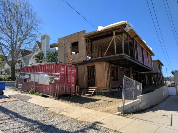 Construction site overview showing wood framing, structural steel beams, and preliminary site grading on a Redondo Beach infill residential lot