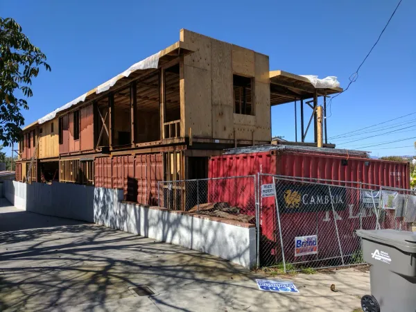 Construction detail showing container and wood-frame integration with concrete retaining wall for site grading, sloped driveway, and drainage grate