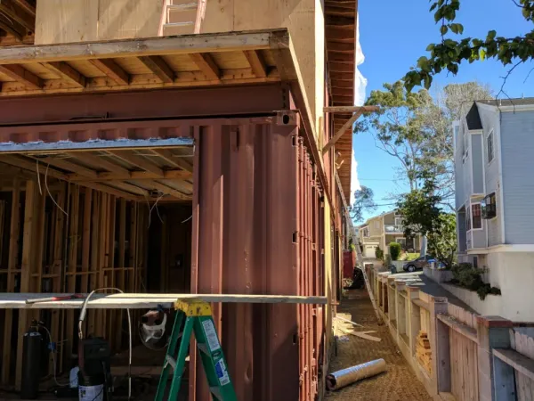 Site grading and soil compaction along foundation of narrow lot with container-based building adjacent to property line