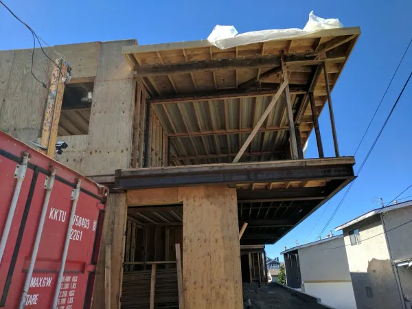 Structural steel I-beam cantilever support for floor assembly during construction of hybrid container and wood-frame residence