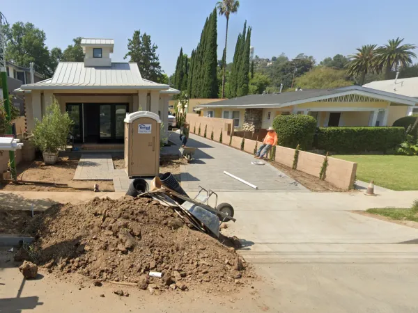 New construction residential property in South Pasadena featuring modern architecture, paver driveway, and retaining walls with neighboring yellow house visible